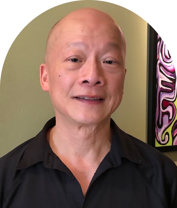 A bald man with shaved head and black shirt.