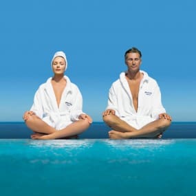 Two people sitting in a pool wearing robes